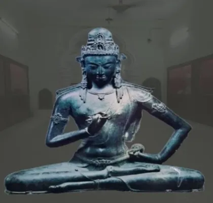 Seated bronze figure wearing a crown, on display in a museum